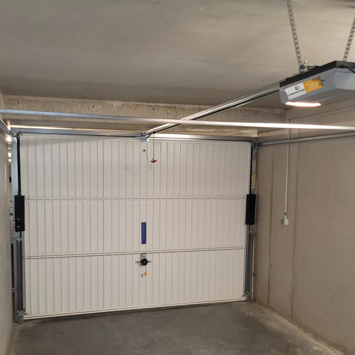 Binnenkant van een gesloten witte garagedeur met horizontale paneelverdeling, voorziende van een automatisch openingssysteem en LED-verlichting.