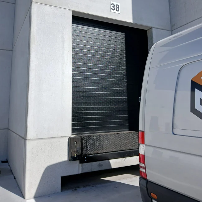 Gesloten rolluik van een laadplatform aan een witte laadbox van een vrachtwagen, genummerd 38.