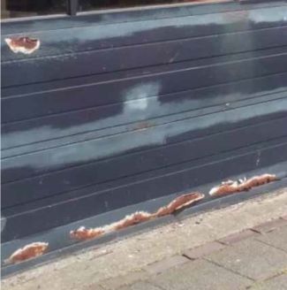 Donkerblauwe sectionaalpoort met roestvorming en vervuiling aan de onderkant, zichtbaar vuil en weersuitwerking.
