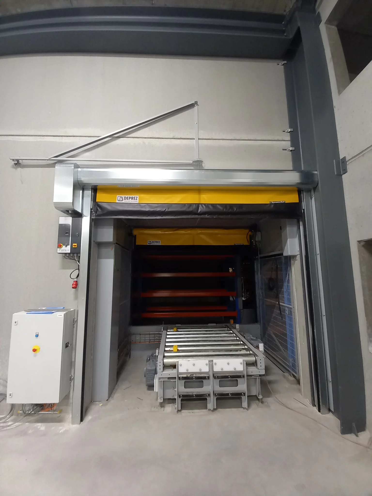 Industriële wasinstallatie met gele Deprez-branding, controlekast links en rollenbandtransporteur voorin.