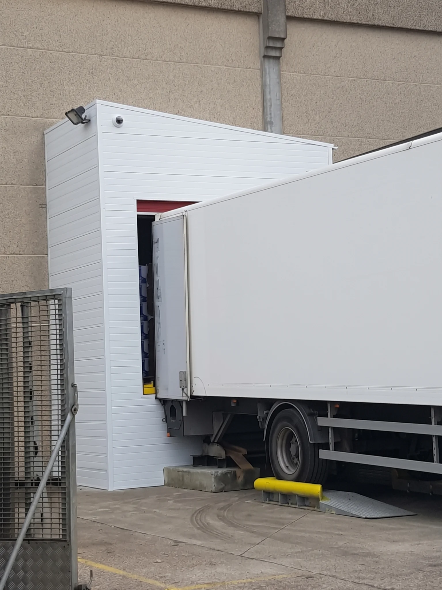 Witte voorzetsluizen aan de zijkant van een laadpakhuis waar een vrachtwagen aansluit voor het laden en lossen van goederen.