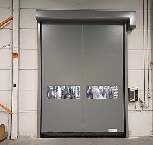 Gesloten automatische schuifdeuren met grijs doek en twee kleine ramen met posters in een witte betegelde muur.