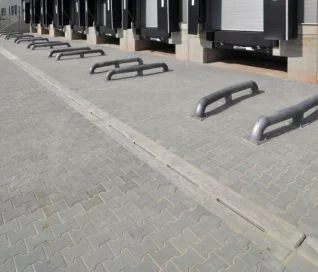 Zwarte stalen geleiders op kasseienbestrating voorkomen dat voertuigen een voetgangerszone binnenrijden.