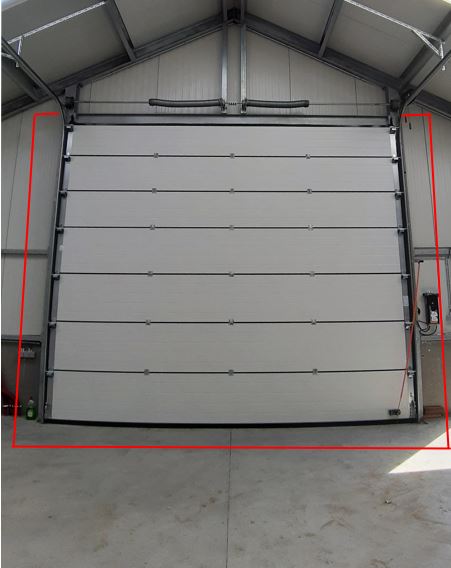 Geopende grijze sectionaaldeur met rode zijkanten in een garageopening met betonnen vloer.
