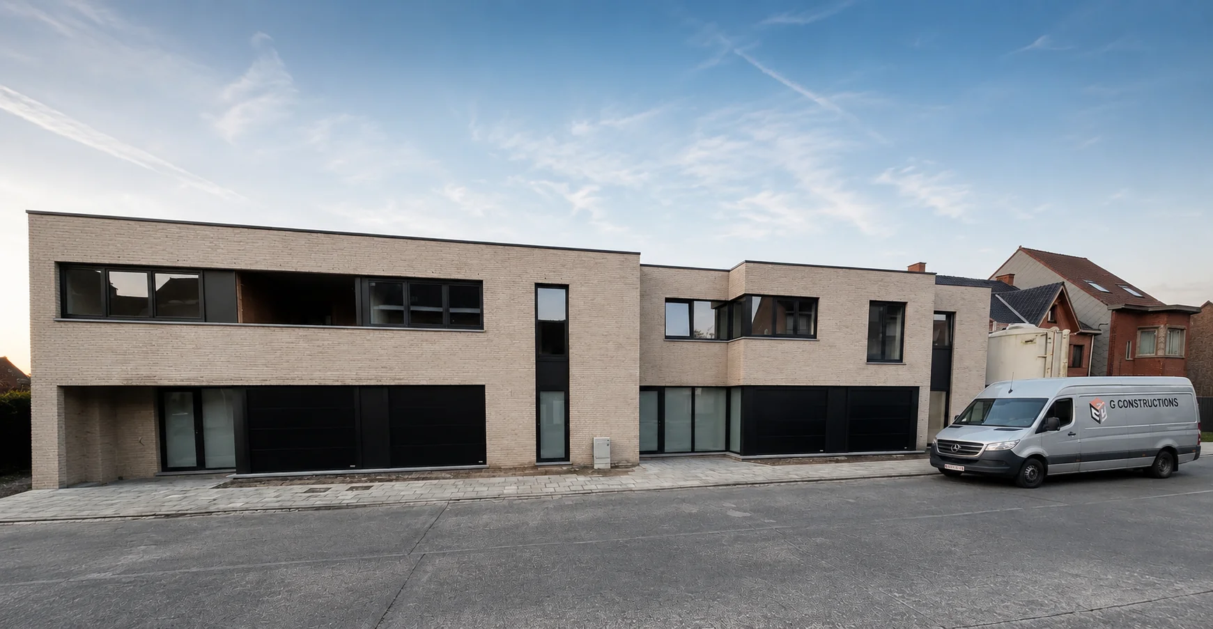Moderne halfvrijstaande woning met twee grote zwarte sectionaalpoorten in de gevel, een bestelwagen ernaast geparkeerd.